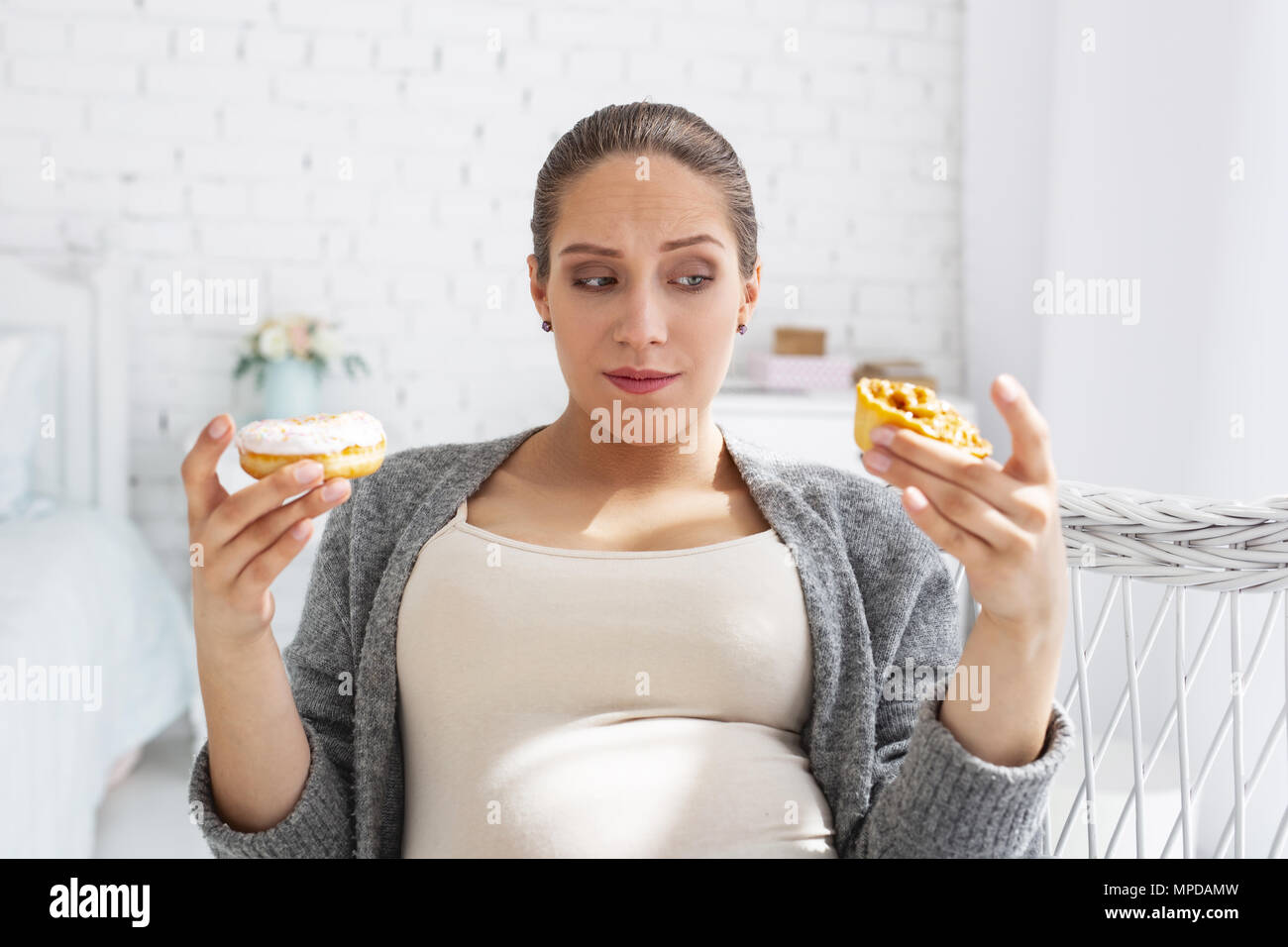 Pensive pregnant woman selecting French pastry Stock Photo - Alamy