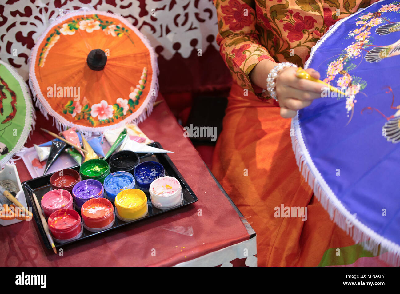 Thai artist showcasing the classical method of umbrella painting at a