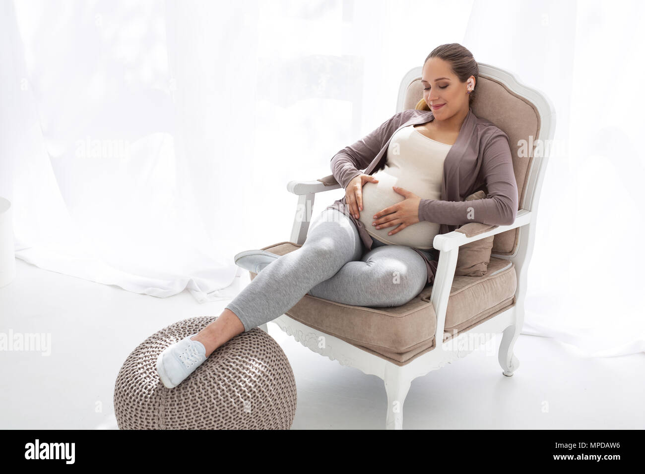 Merry pregnant woman hugging belly Stock Photo - Alamy