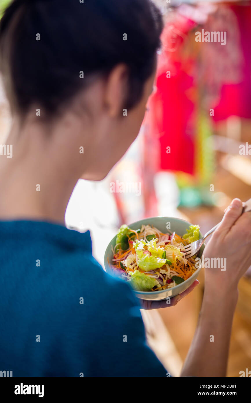 A young woman eating a salad in a bowl Stock Photo