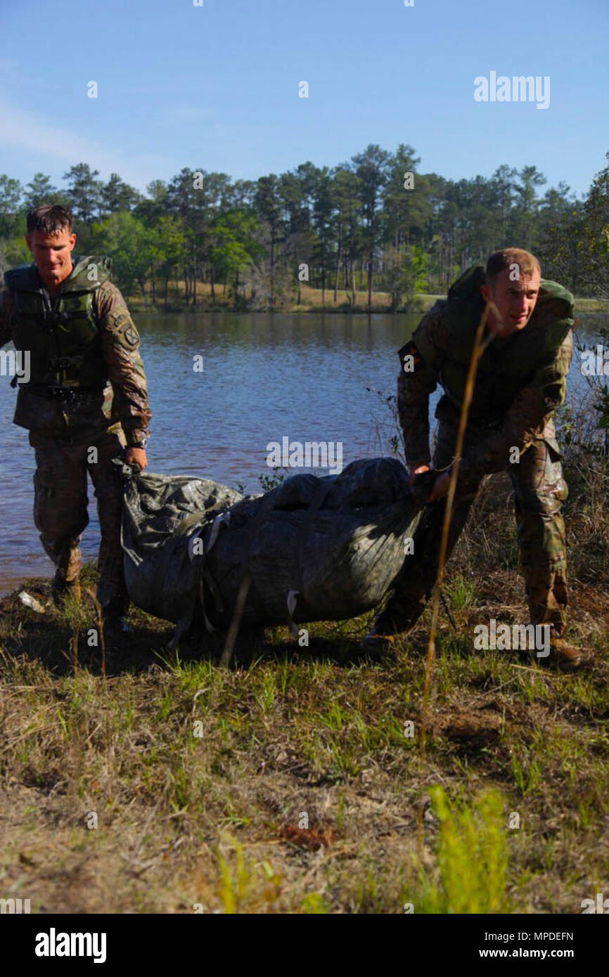 U.S. Army Rangers 1st Lt. Matthew Slocum and 1st Lt. Christopher Gaziano, assigned to the 10th Mountain Division, pull their rucksacks from Victory Pond during combat water survival portion of the Best Ranger Competition 2017 on Fort Benning, Ga., April 9, 2017. The 34th annual David E. Grange Jr. Best Ranger Competition 2017 is a three-day event consisting of challenges to test competitors physical, mental, and technical capabilities. Stock Photo