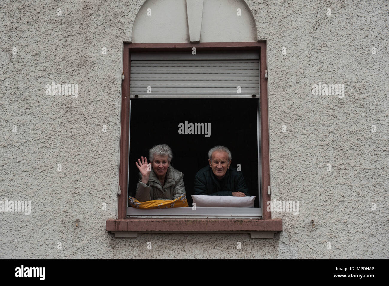 Two elderly people peer out their house window during fasching, a festival held across Europe, in the city of Ramstein, Germany, Feb. 28, 2017. The festival season is celebrated by people from Germany, Switzerland and Austria. (U.S. Air Force photo by Senior Airman Lane T. Plummer) Stock Photo