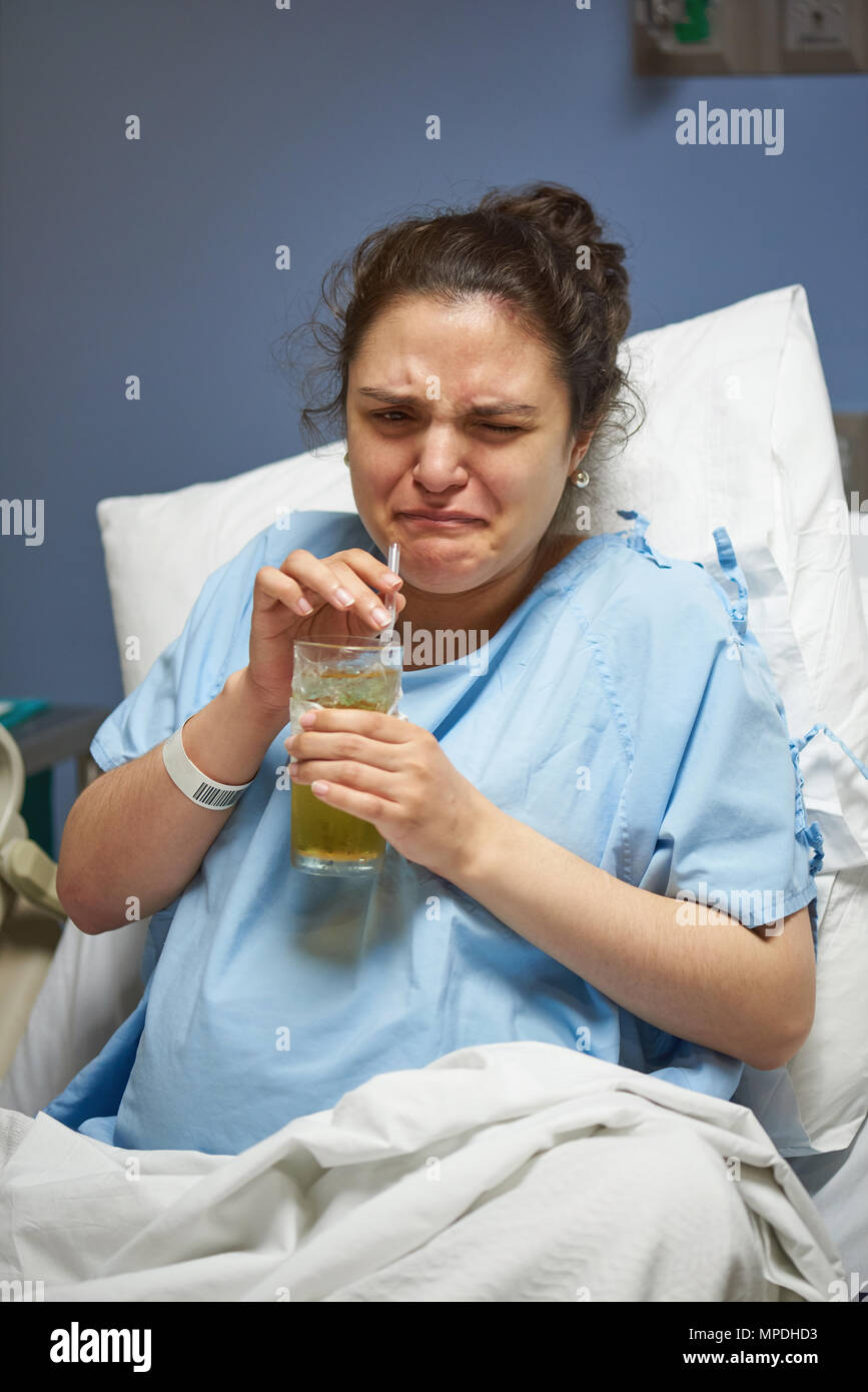 Woman patient drink sour liquid in hospital room Stock Photo