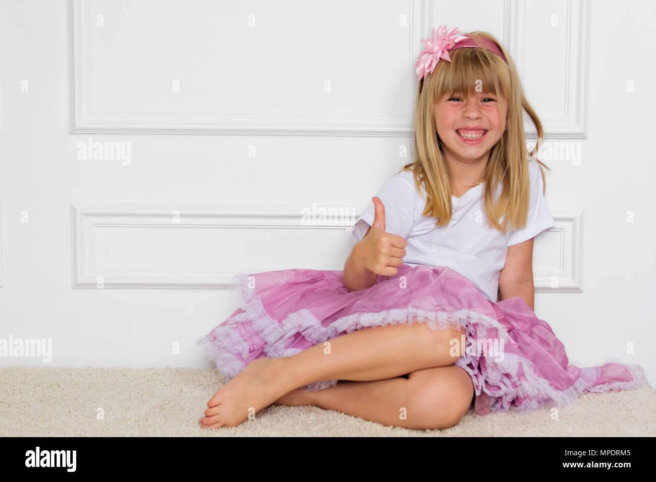 Little girl in a beautiful dress sits near a wall Stock Photo - Alamy