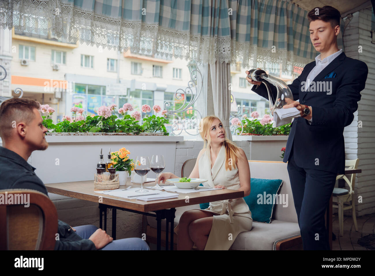 The sommelier pours the wine into the decanter near the guests in the restaurant. romantic date. wine tasting Stock Photo