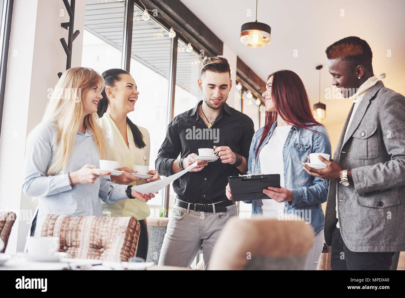 Successful young business people are talking and smiling during the coffee break in office Stock Photo