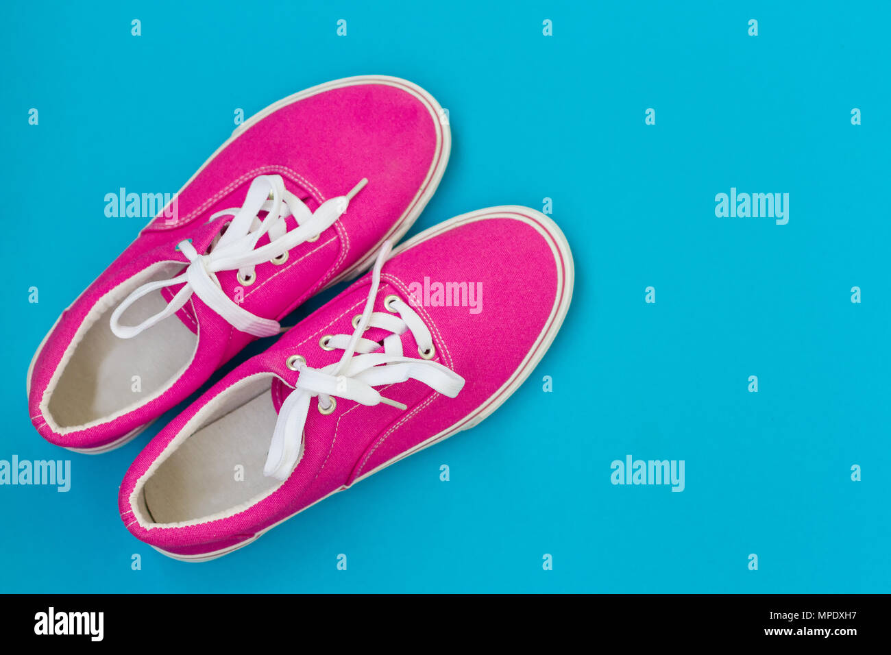 Pink sneakers with laces on a blue background Stock Photo - Alamy