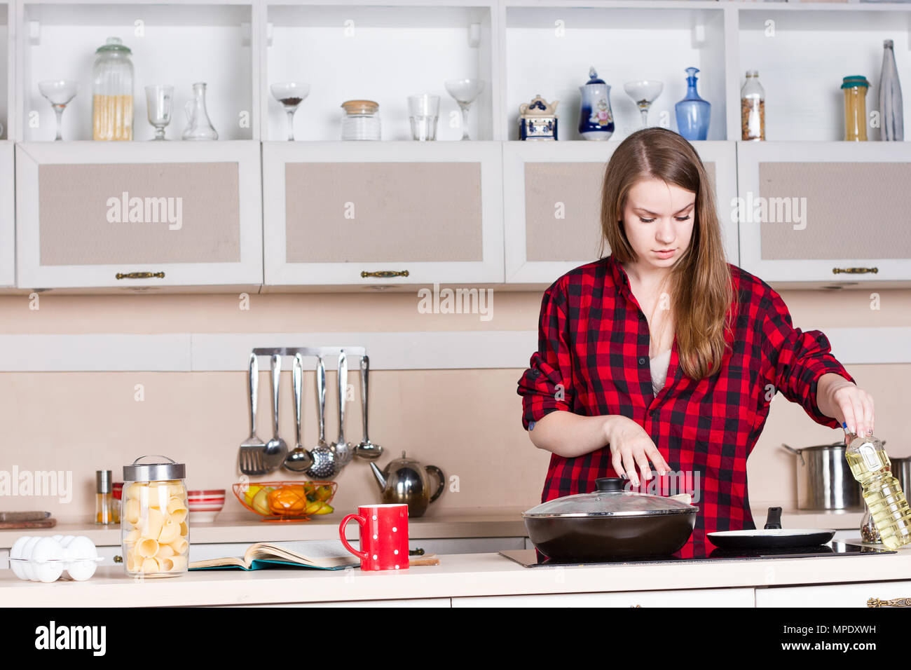 Girl with long flowing hair in a red shirt male prepares in the kitchen