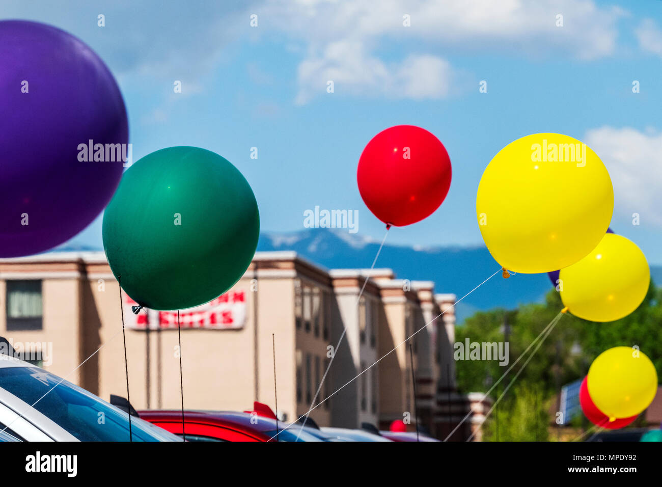 Colorful balloons; windy day; automobile dealership; Salida; Colorado; USA Stock Photo