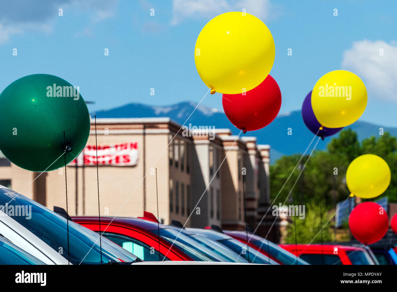 Colorful balloons; windy day; automobile dealership; Salida; Colorado; USA Stock Photo