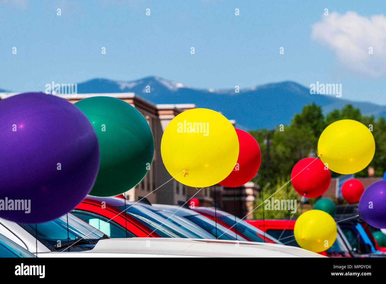 Colorful balloons; windy day; automobile dealership; Salida; Colorado; USA Stock Photo