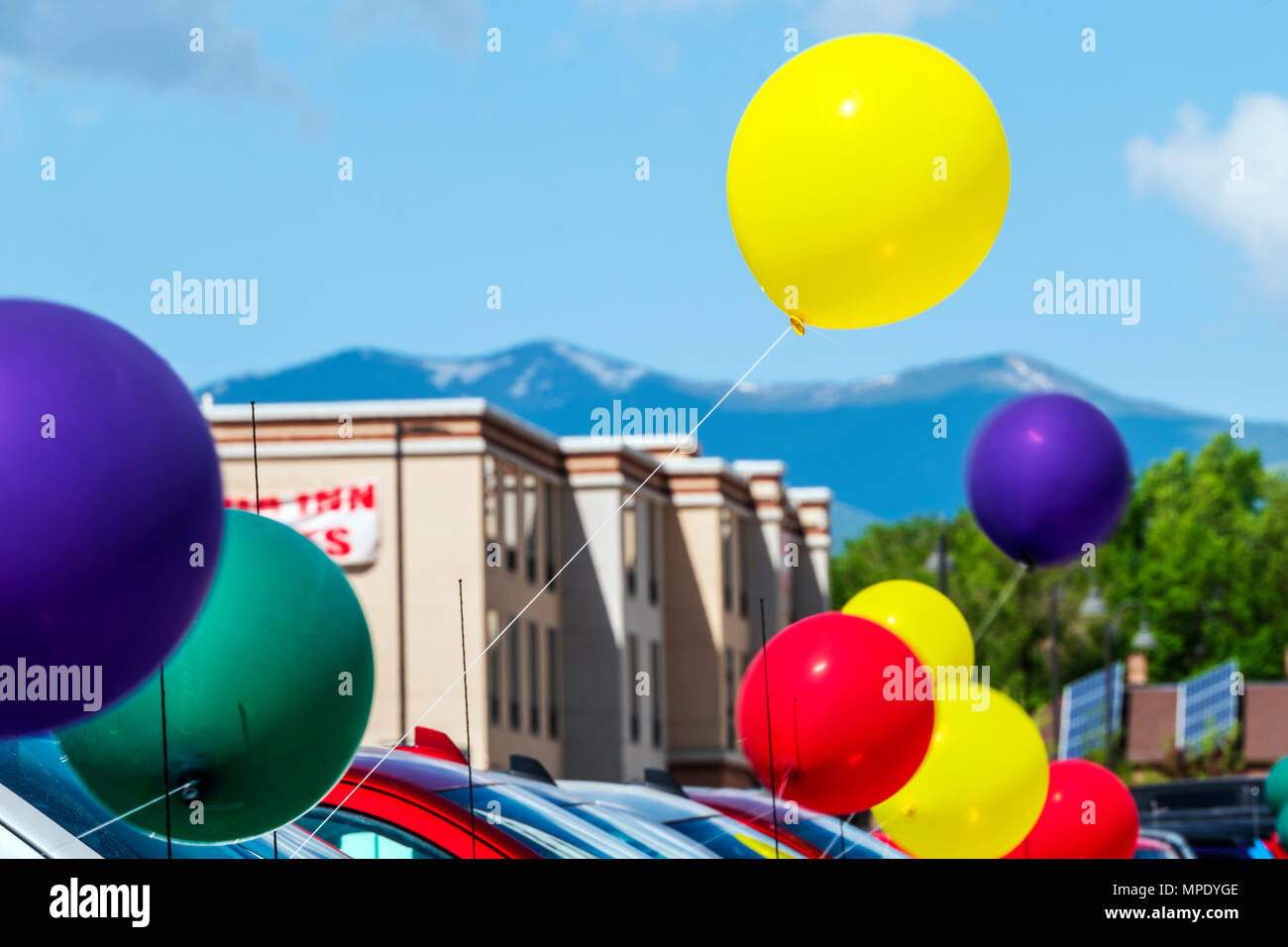 Pan; blur; motion view of colorful balloons; windy day; automobile dealership; Salida; Colorado; USA Stock Photo