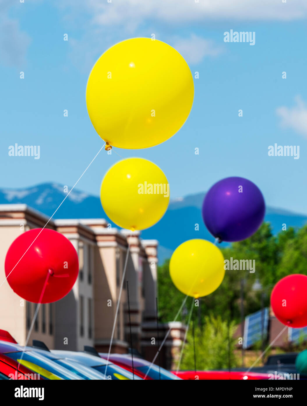 Pan; blur; motion view of colorful balloons; windy day; automobile dealership; Salida; Colorado; USA Stock Photo