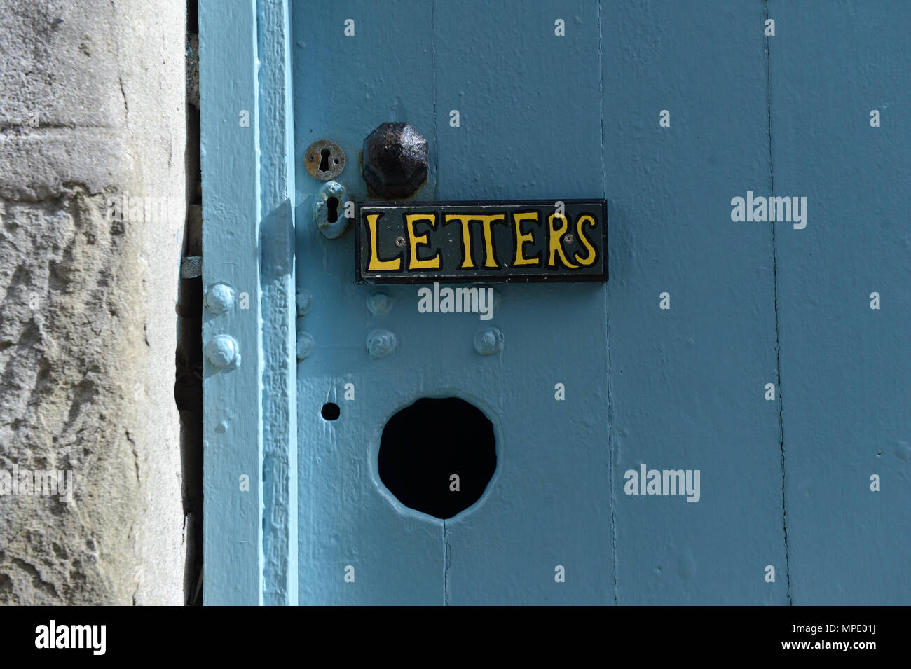 Unusual letter box with a hole in the door for letters to be delivered with hand painted sign Letters above it Stock Photo