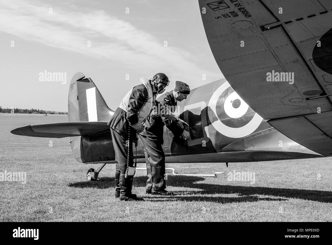 Battle of Britain era Spitfire Mk1 with pilot & ground crew engineer re-enactors discussing apparent battle damage. Supermarine Spitfire Mark 1 plane Stock Photo