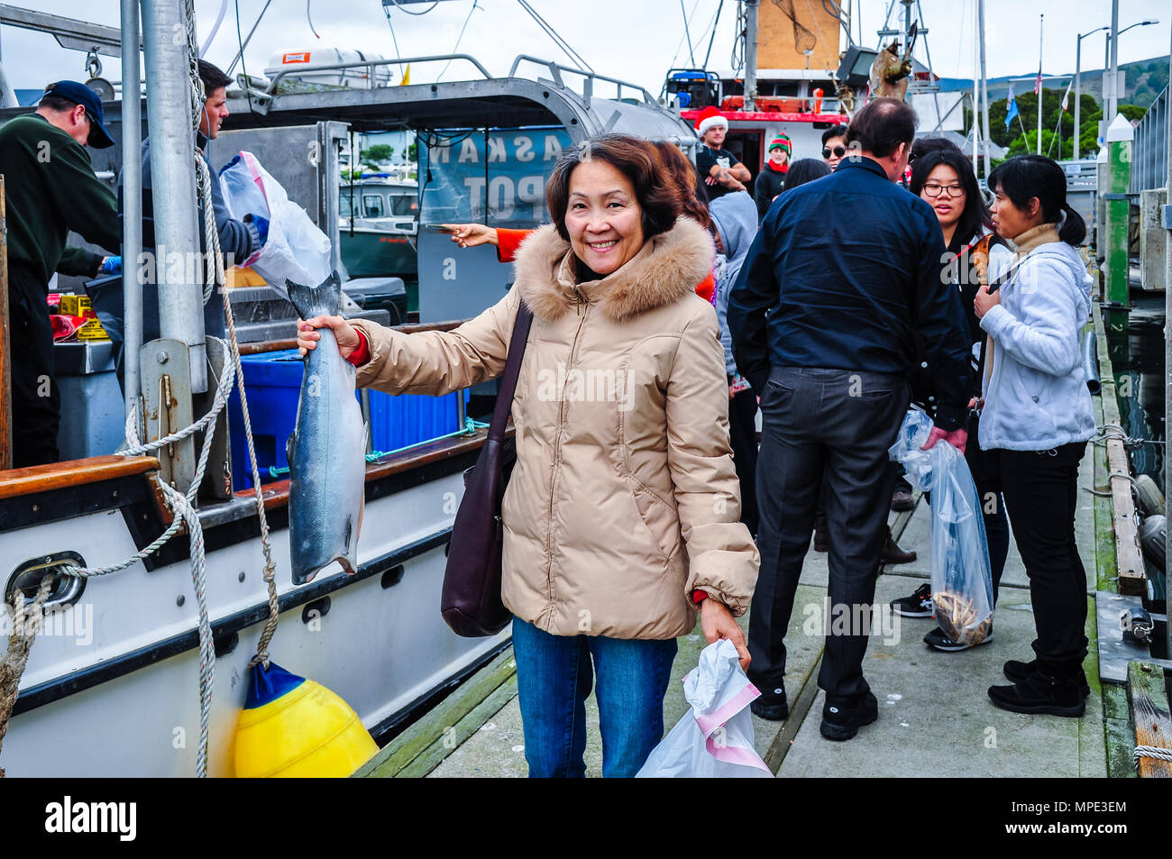 Half Moon Bay, California - Foreign tourist buys fish and crab from fishermen at Pillar Point Harbor, Half Moon Bay, CA Stock Photo