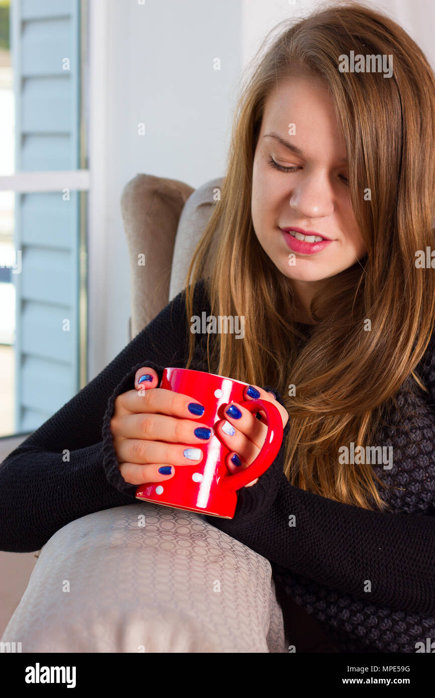 beautiful woman drinking coffee in the morning sitting by the window