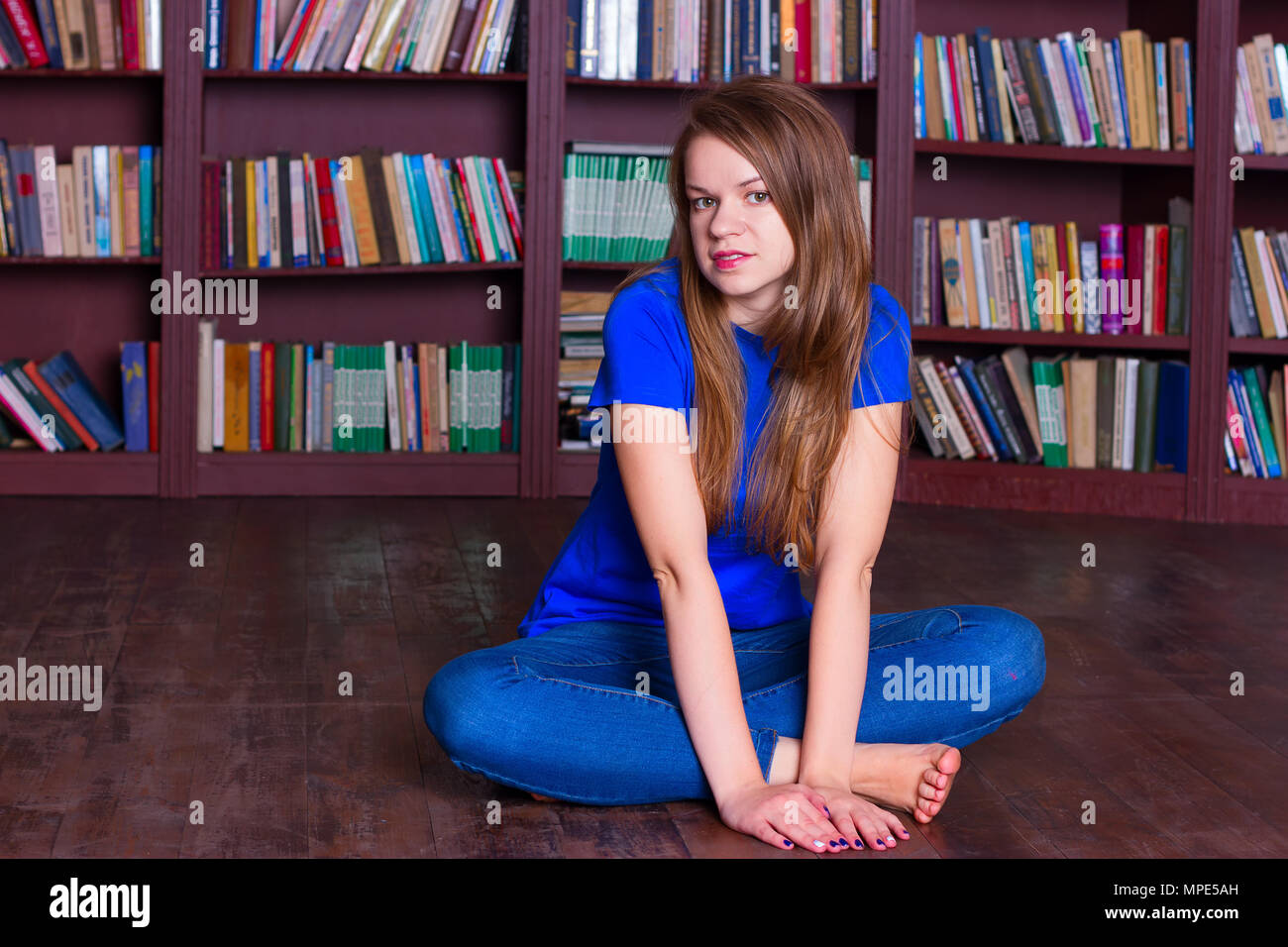 A girl sits on the floor in the library Stock Photo - Alamy