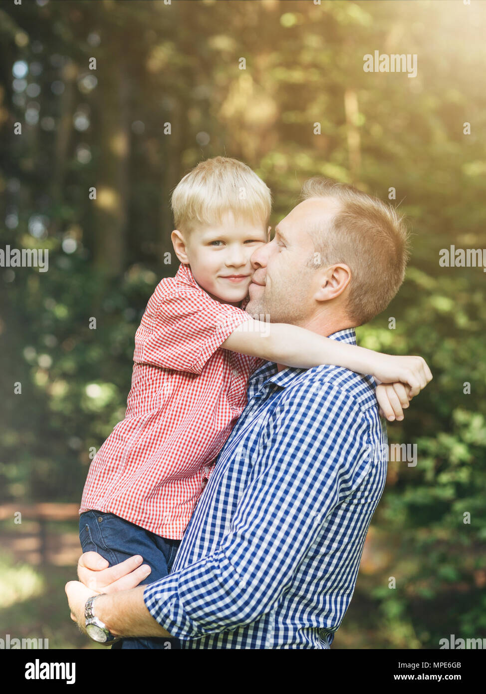 Sincere embrace of father and son in the park. Masculinity concept. Candid people with real emotion. Family, love. Stock Photo