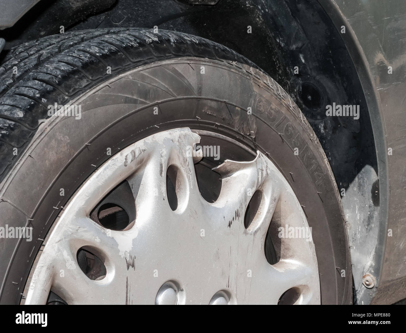 Hubcap damaged, broken and scratched from an automobile accident. Plastic cover for a steel wheel of a car. Close up detail. Tire dimensions not subje Stock Photo