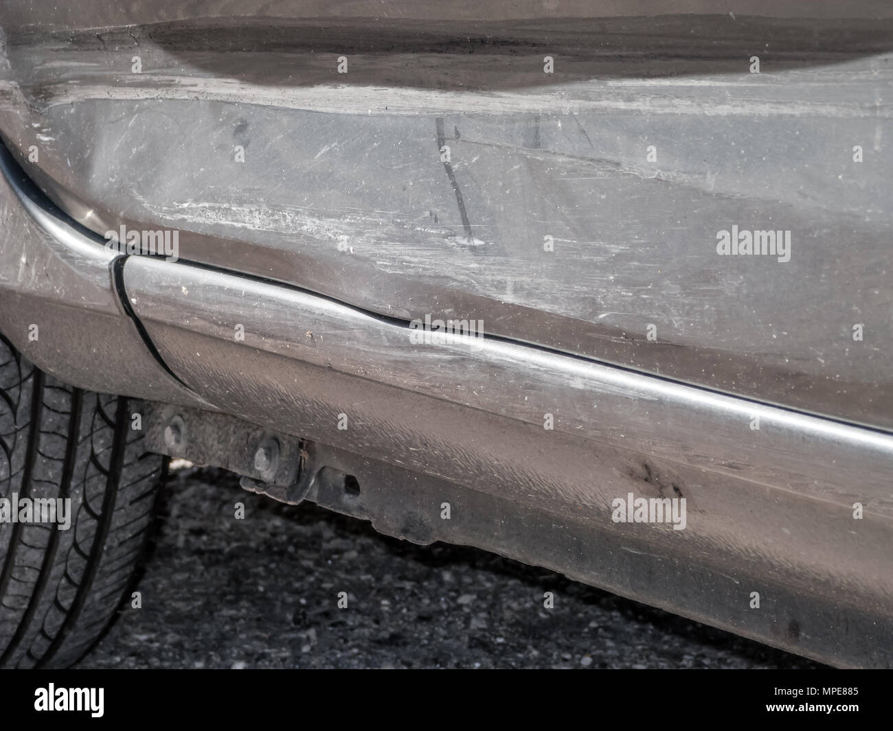 Close up detail of a dented driver door from a car crash or automobile accident. Bent and distorted metal with large dent and body paint scratched Stock Photo