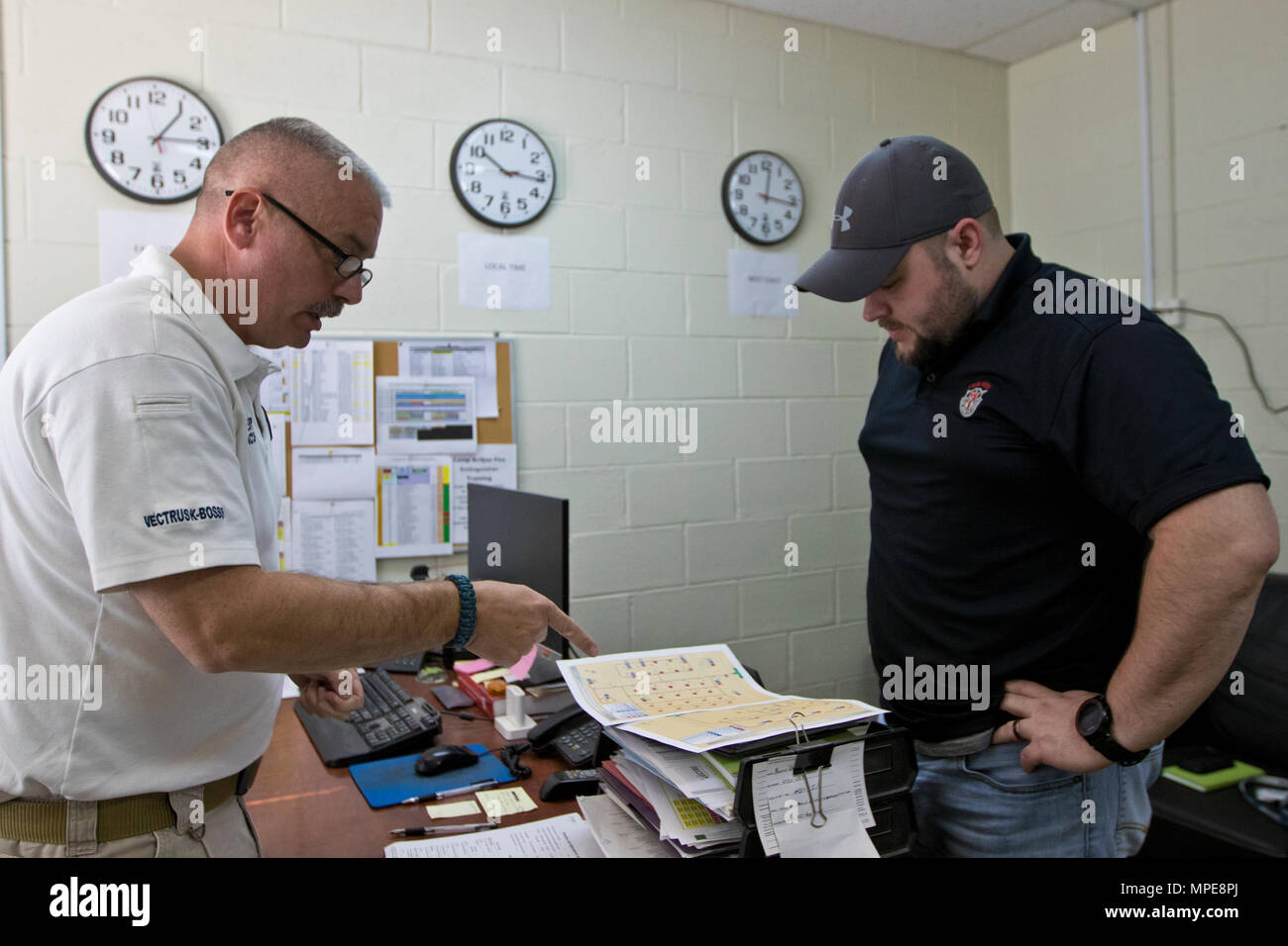 James Wenger, Assistant Chief for the Area Support Group – Kuwait joint emergency service station, (left), shows James Lyndsey, an Explosives Safety Specialist with the U.S. Army Defense Ammunition Center, (right), documents and maps during the 2017 Worldwide Ammunition Logistics and Explosives Safety Review in Camp Arifjan, Kuwait, on Feb. 7, 2017. (U.S. Army Photo by Staff Sgt. Dalton Smith) Stock Photo
