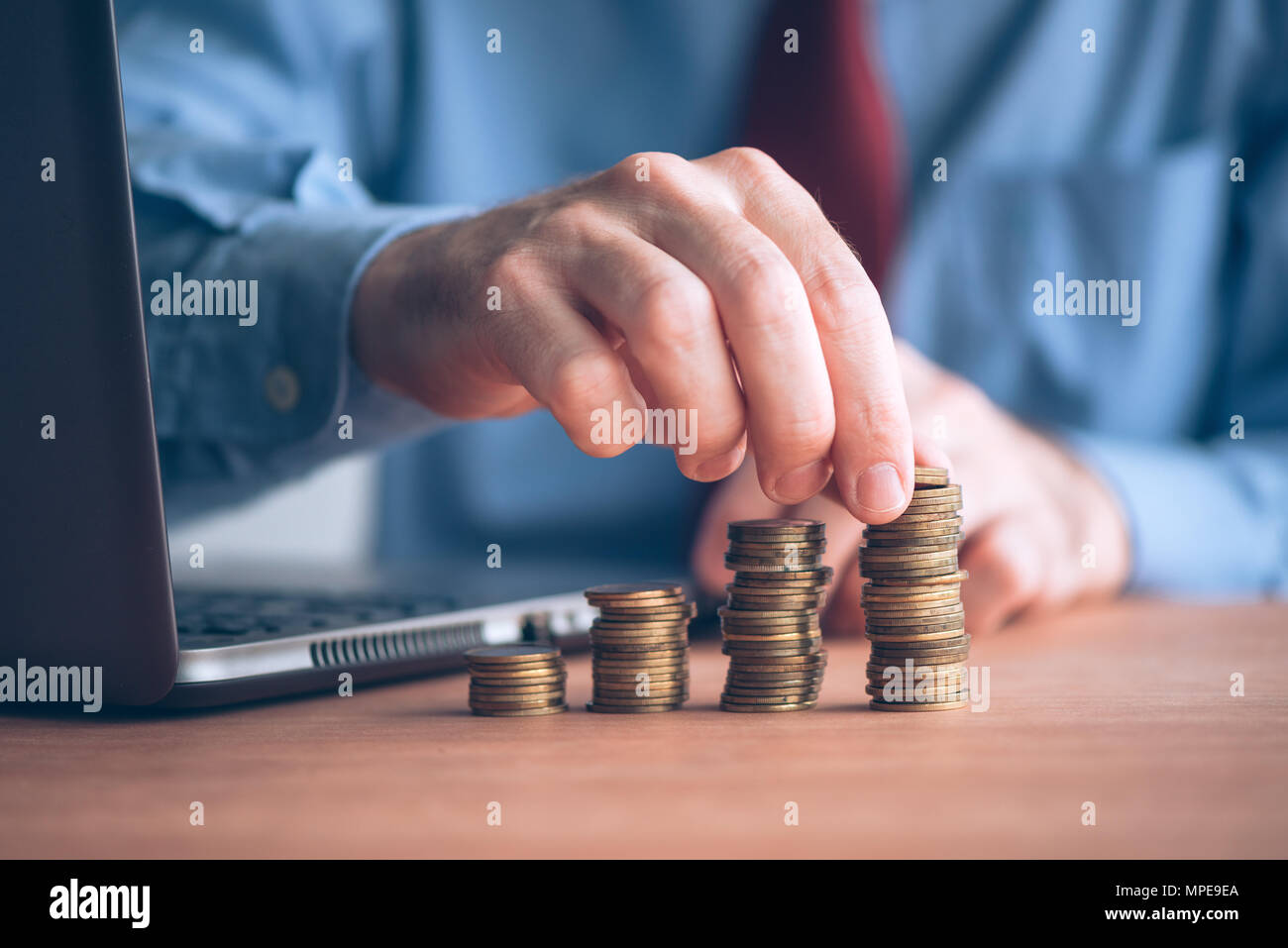 Building savings and increase emergency funds, businessman with stacked money coins on office desk Stock Photo