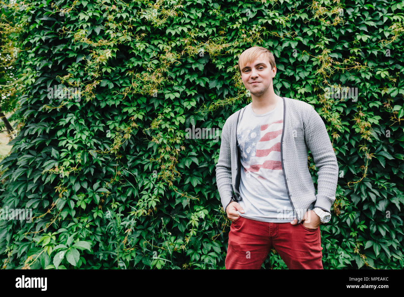 Portrait of a stylish man against a green foliage background Stock ...