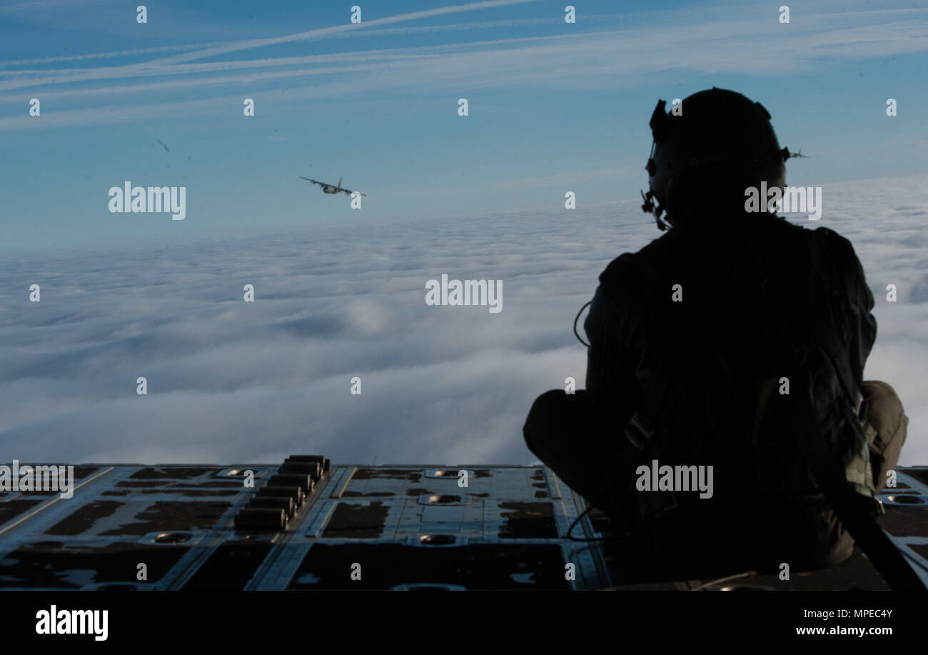 Airman 1st Class Quinn Harris, 37th Airlift Squadron loadmaster, peers over the skies at another C-130J Super Hercules flying over blanket of clouds in Germany, Feb. 10, 2017. During the Korean War, the squadron flew airborne assaults at Sukchon and Munsan-ni and aerial transportation between Japan and Korea. (U.S. Air Force photo by Air Force Senior Airman Lane T. Plummer) Stock Photo