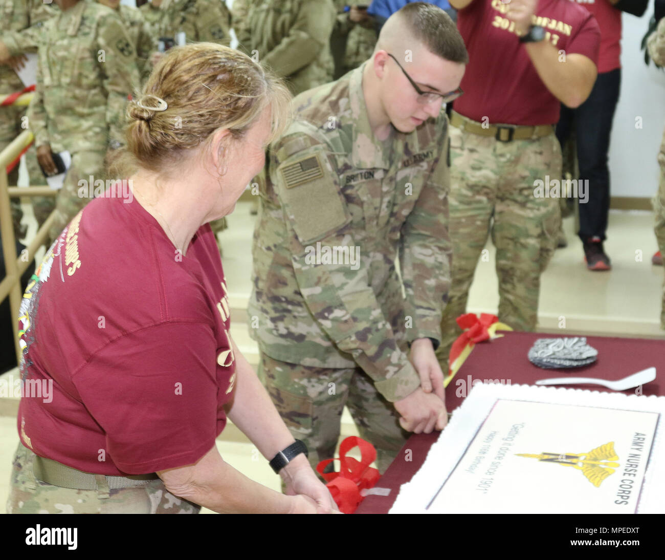 CAMP ARIFJAN, Kuwait -- Col. Belinda Spencer (left), critical care nurse, and Pfc. Richard Britton (center), a combat medic, both with the 31st Combat Support Hospital, cut the birthday cake honoring the 116th Army Nurse Corp birthday at Camp Arifjan, Kuwait, Feb. 2, 2017. (U.S. Army photo by Sgt. Tom Wade, USARCENT PAO) Stock Photo