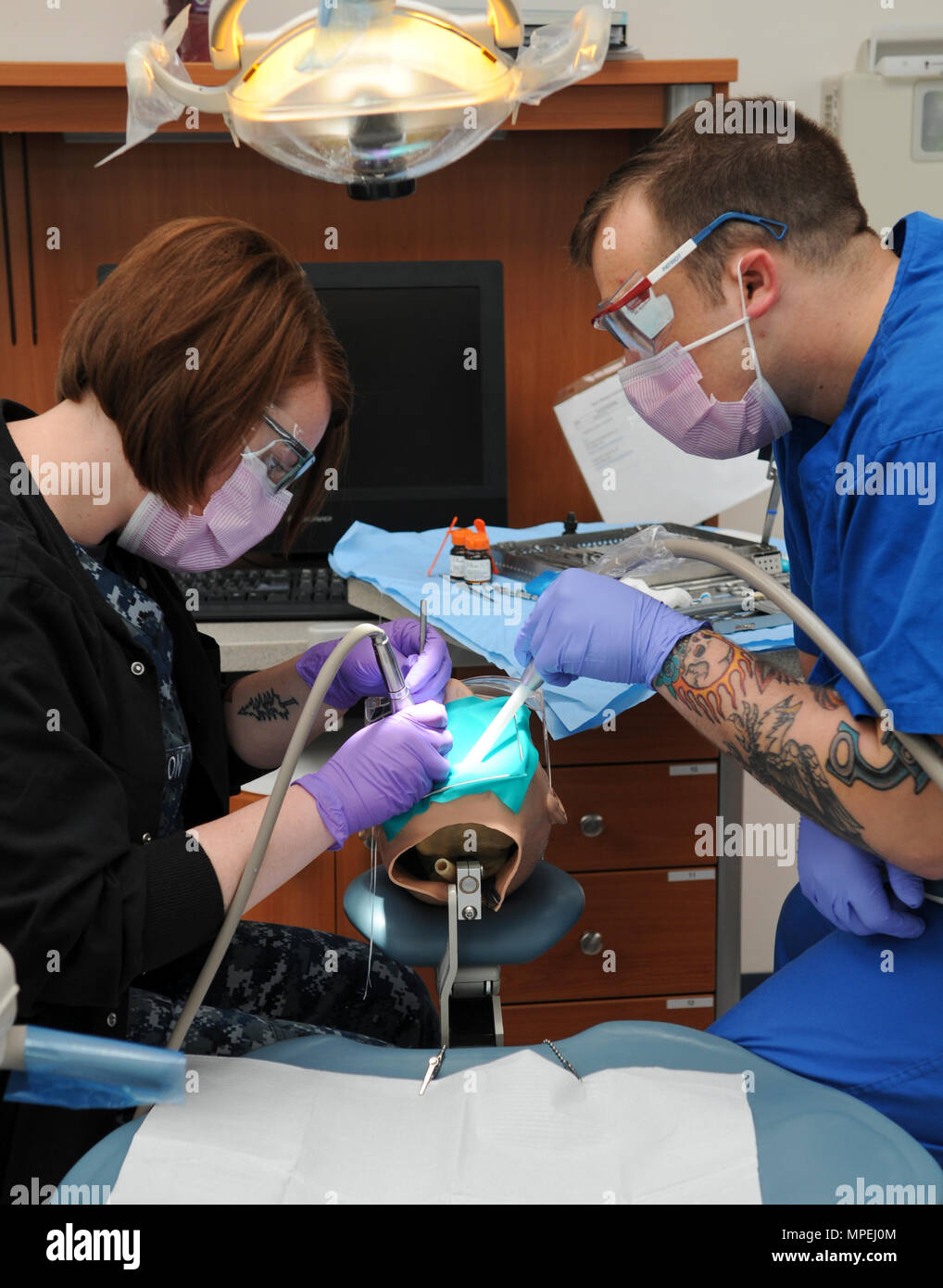 SAN ANTONIO (Feb. 14, 2017) Hospital Corpsman 2nd Class Tandem Anderson, left, a dental instructor at the Medical Education and Training Campus (METC), trains Hospitalman Corbin Morgan on chair-side assistance as part of the Navy Dental Assistant Program at METC on board Joint Base San Antonio - Fort Sam Houston, Texas. The program is designed to give students the basic understanding of oral anatomy, dental administration and dental procedures and provides hands-on training in infection control, general chair-side assistance and radiology procedures. (U.S. Navy photo by Mass Communication Spec Stock Photo