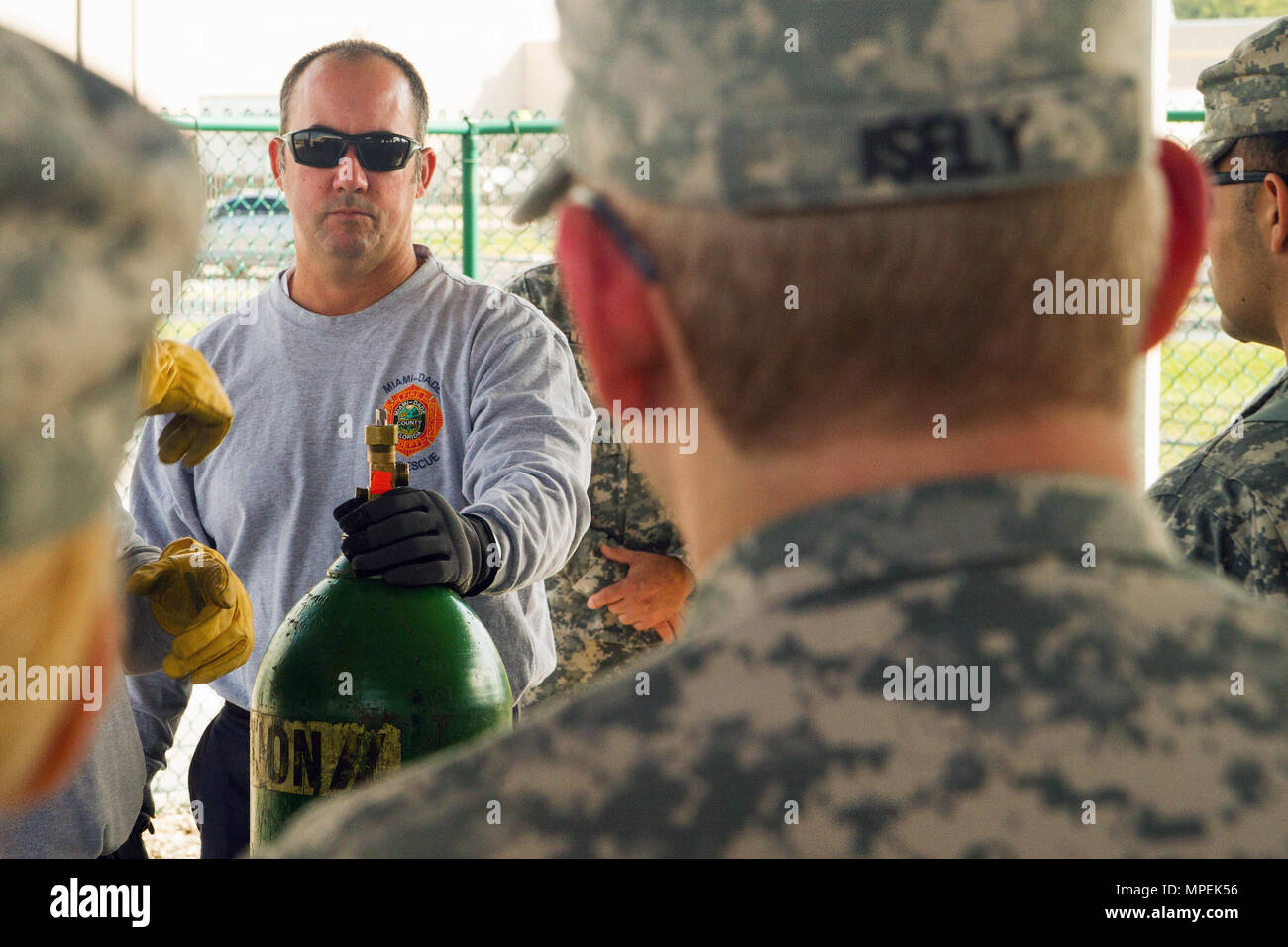 Firefighter David Guerra, a flight medic with the Miami-Dade Fire Rescue Department (MDFR), explains how to cap a valve leak on a gas cylinder to Army Reserve Soldiers assigned to the 329th Chemical, Biological, Radiological, and Nuclear (CBRN) Company (Reconnaissance and Surveillance), during training at the MDFR training facility on Feb. 17, 2017 in Doral, Fla. The 329th CBRN Company, from Orlando, Fla., the Army Reserve’s 469th Ground Ambulance Company, from Wichita, Kan., and the Florida National Guard’s Civil Support Team, spent the day training with MDFR firefighters and learned about to Stock Photo