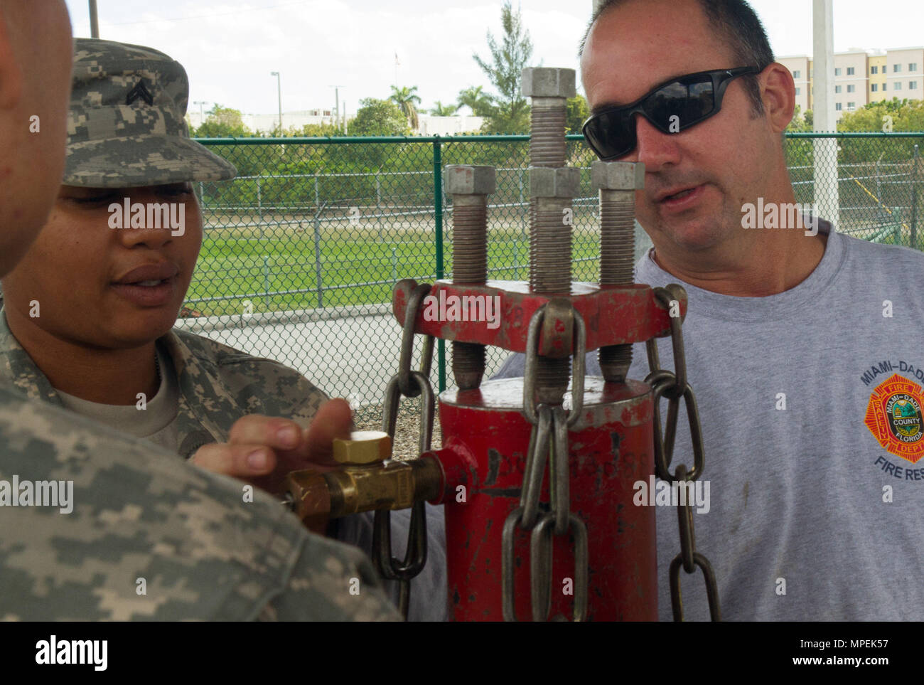 Firefighter David Guerra, a flight medic with the Miami-Dade Fire Rescue Department (MDFR), assists Army Reserve Cpl. Shalandis Johnson on how to cap a gas cylinder during training at the MDFR training facility on Feb. 17, 2017 in Doral, Fla. Johnson, who lives in Orlando, Fla., is a Chemical, Biological, Radiological, and Nuclear (CBRN) Specialist assigned to the 329th CBRN Company (Reconnaissance and Surveillance), which is based in Orlando. The 329th CBRN Company, the Army Reserve’s 469th Ground Ambulance Company, from Wichita, Kan., and the Florida National Guard’s Civil Support Team, spen Stock Photo