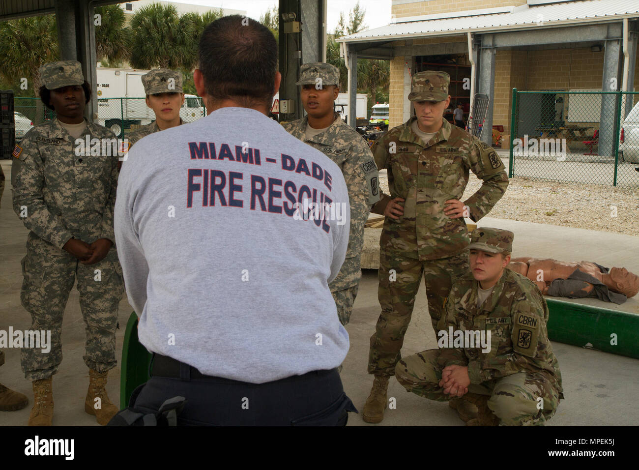 Firefighter David Guerra, a flight medic with the Miami-Dade Fire Rescue Department (MDFR), talks with Army Reserve Soldiers assigned to the 329th Chemical, Biological, Radiological, and Nuclear (CBRN) Company (Reconnaissance and Surveillance), about how to safely and properly cap leaks in gas cylinders during joint training at the MDFR training facility on Feb. 17, 2017 in Doral, Fla. The 329th CBRN Company, from Orlando, Fla., the Army Reserve’s 469th Ground Ambulance Company, from Wichita, Kan., and the Florida National Guard’s Civil Support Team, spent the day training with MDFR firefighte Stock Photo