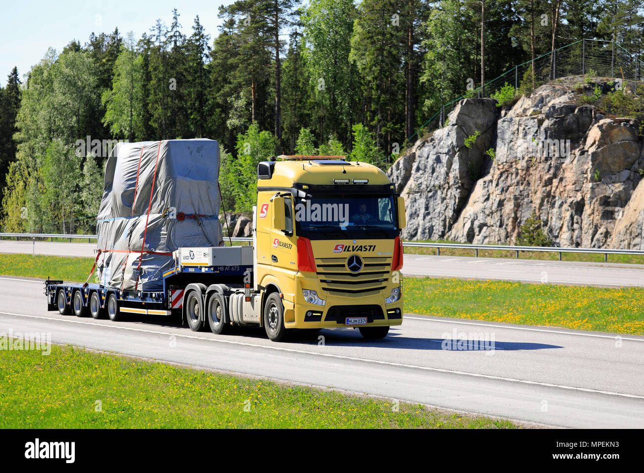 Yellow Mercedes-Benz Actros 3351 semi trailer of Silvasti Heavy transports industrial object on motorway in the summer. Paimio, Finland - May 18, 2018 Stock Photo