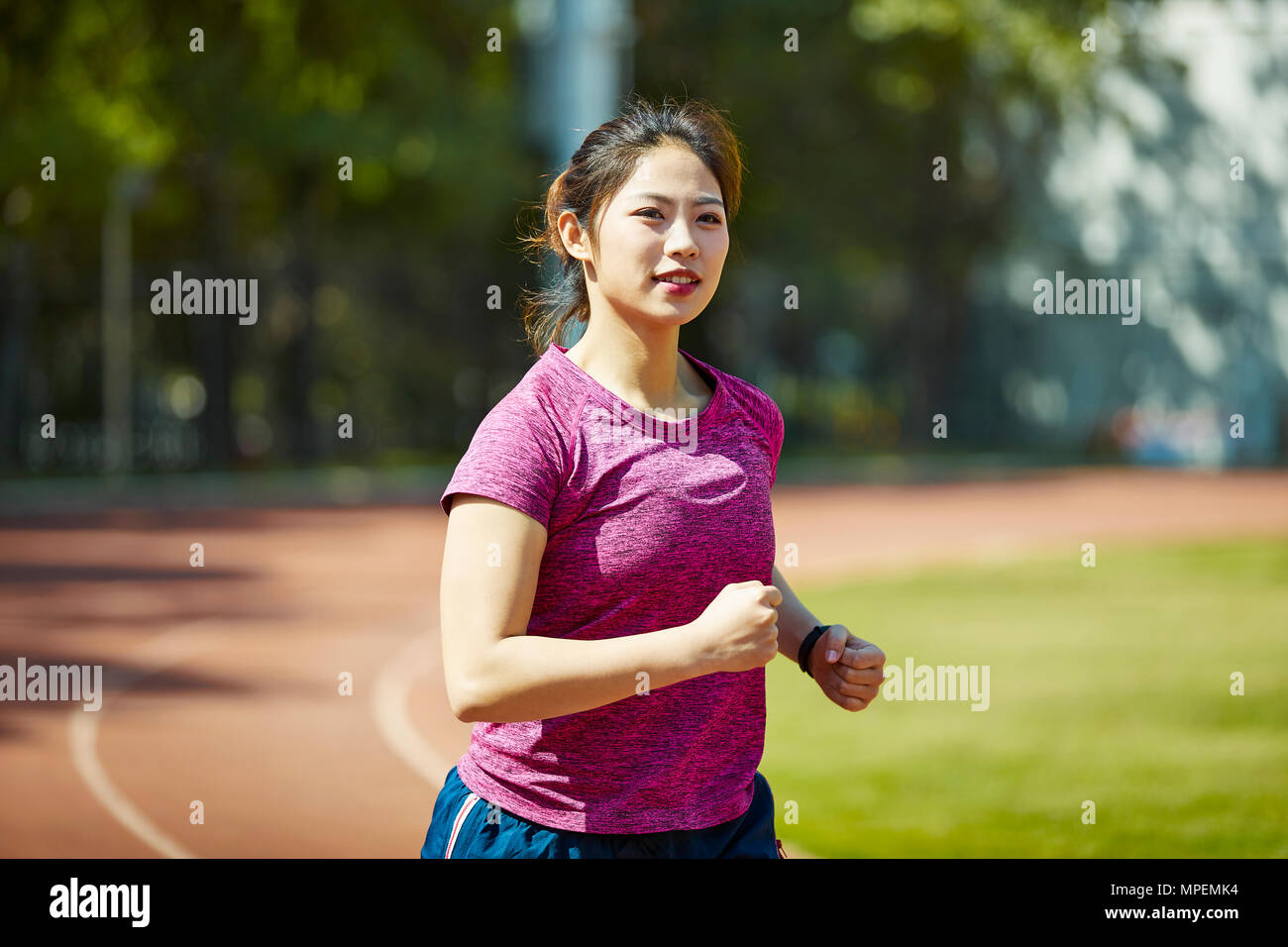young asian female athlete running training on track outdoors. Stock Photo
