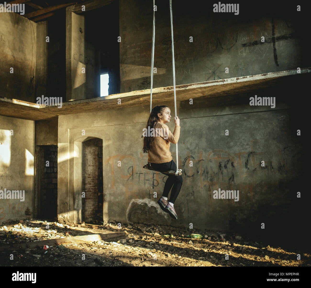 Girl rocking on a swing in a destroyed building on the seafront in Okhamchira, Abkhazia, Georgia Stock Photo