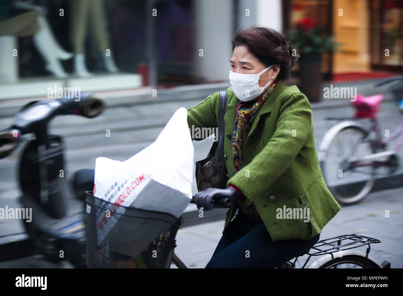 Chinese woman riding a bike over the polution of China Stock Photo