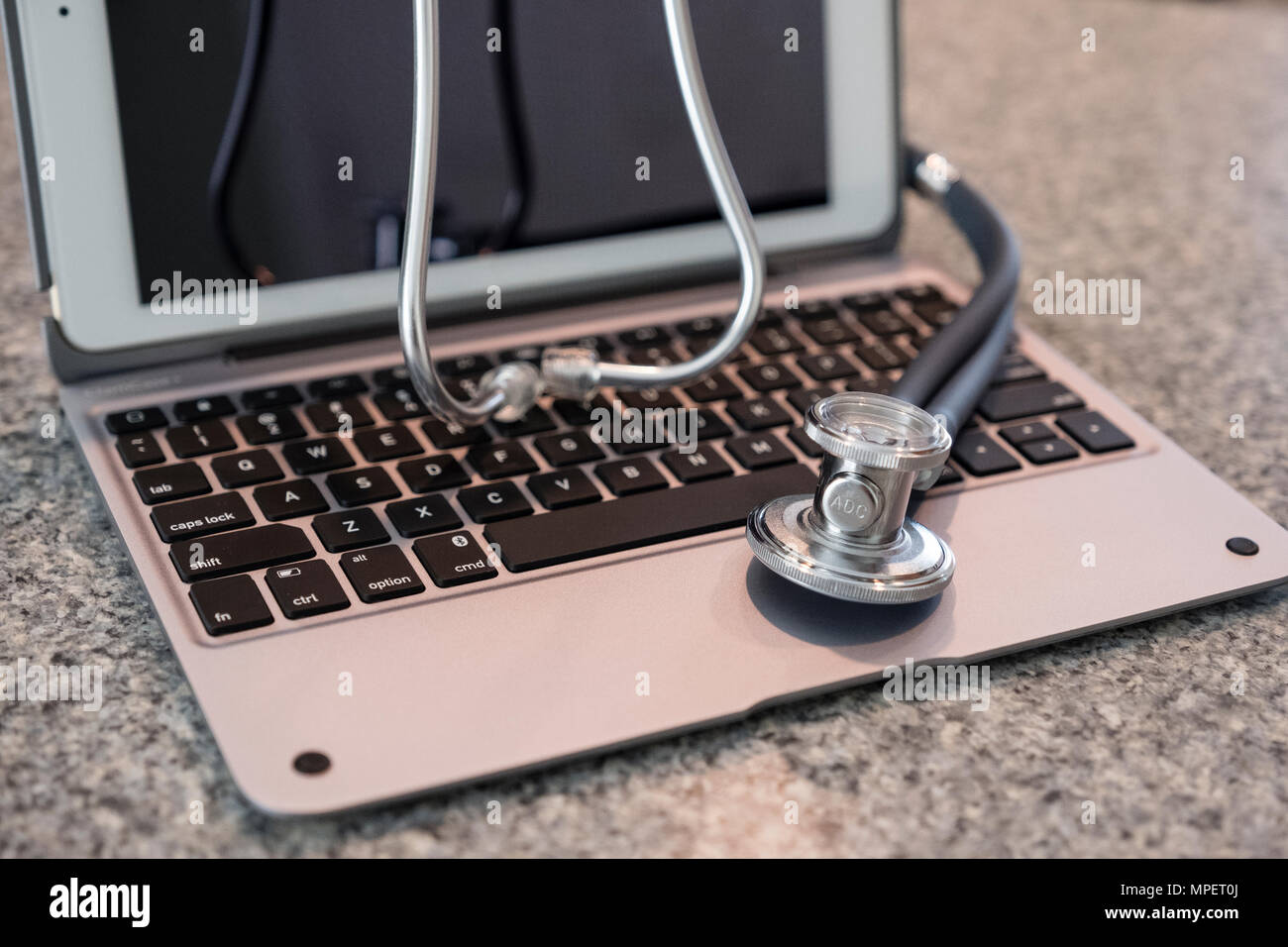 Stethoscope on keyboard countertop ready for use and data entry by medical professional Stock Photo