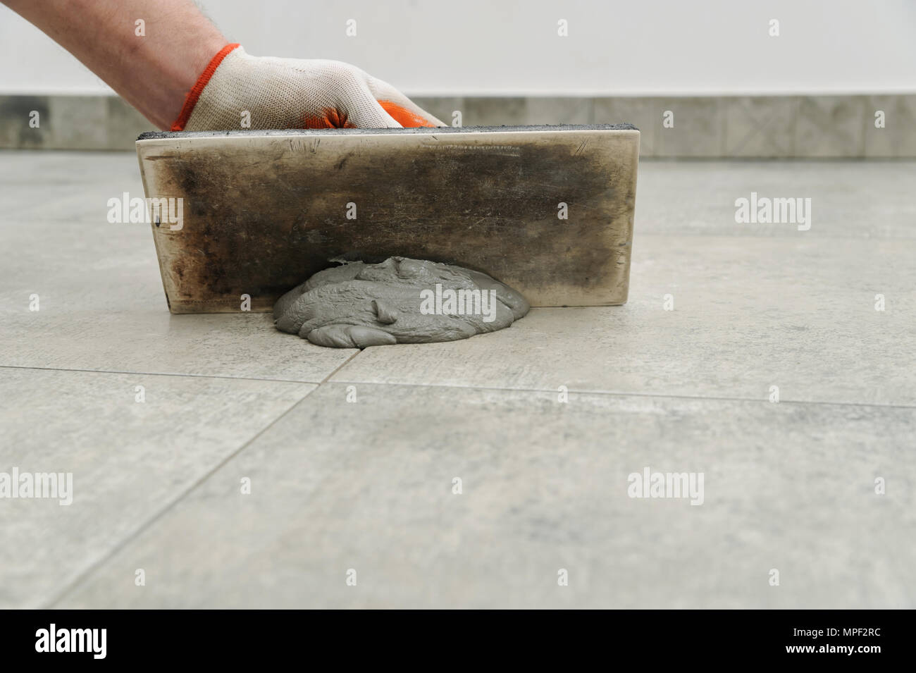 Grouting ceramic tiles. Tilers filling the space between tiles using a rubber trowel Stock Photo