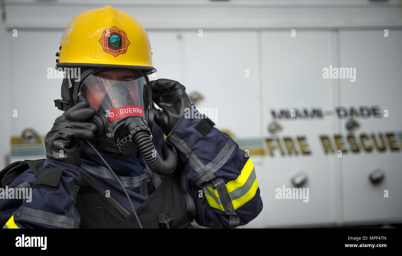 David Guerra, Miami-Dade Fire Rescue air rescue flight medic, adjusts protective equipment during a hazardous material decontamination exercise on the Port of Miami, Fla. Feb 18, 2017.The exercise was led by Miami-Dade Fire Rescue and U.S. Army North under the supervision of U.S. Northern Command and provided soldiers and first responders the unique experience of operating together in a major metropolitan city. (U.S. Air Force photo by Staff Sgt. Cory D. Payne) Stock Photo