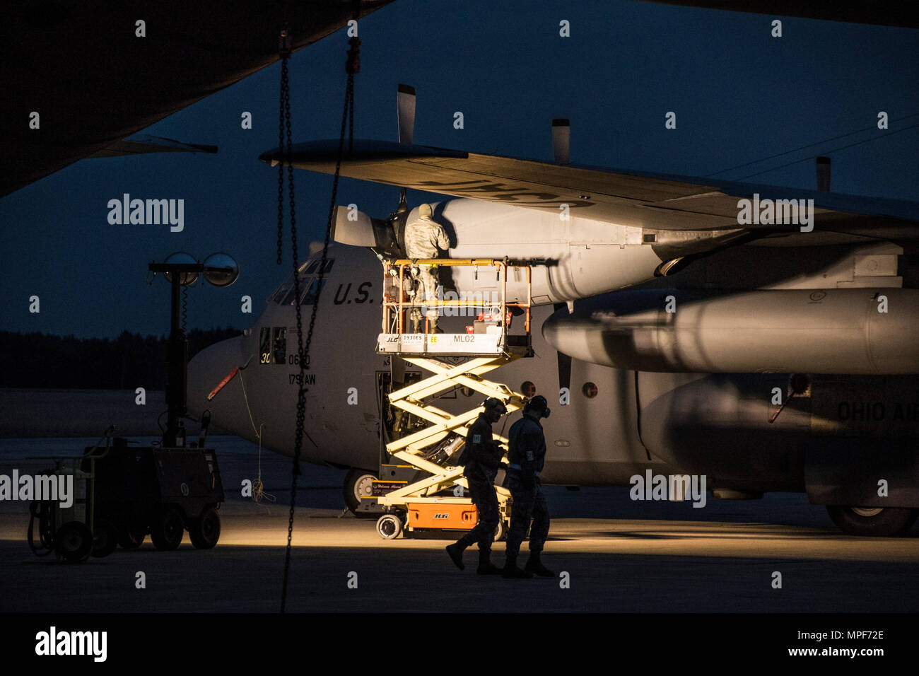 179th Airlift Wing Maintenance members work on the engine of a C-130H Hercules as the sun rises, Feb. 21, 2017, at the 179th Airlift Wing, Mansfield, Ohio.  The 179th Airlift Wing is always on mission to be the first choice to respond to community, state and federal missions with a trusted team of highly qualified Airmen. (U.S. Air National Guard photo by 1st Lt. Paul Stennett/Released) Stock Photo