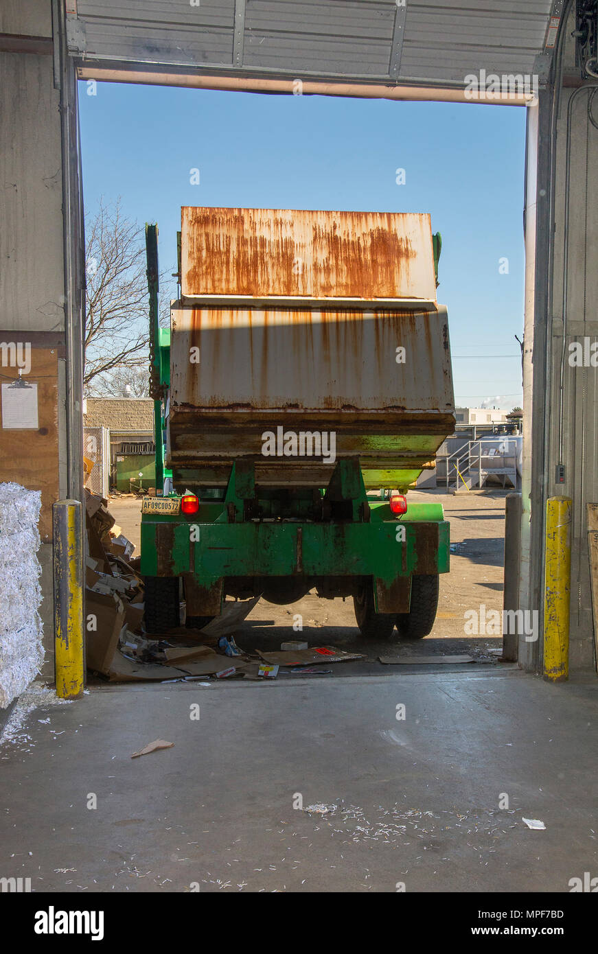 A truck carrying a dumpster filled with ink toner cartridges backs into
