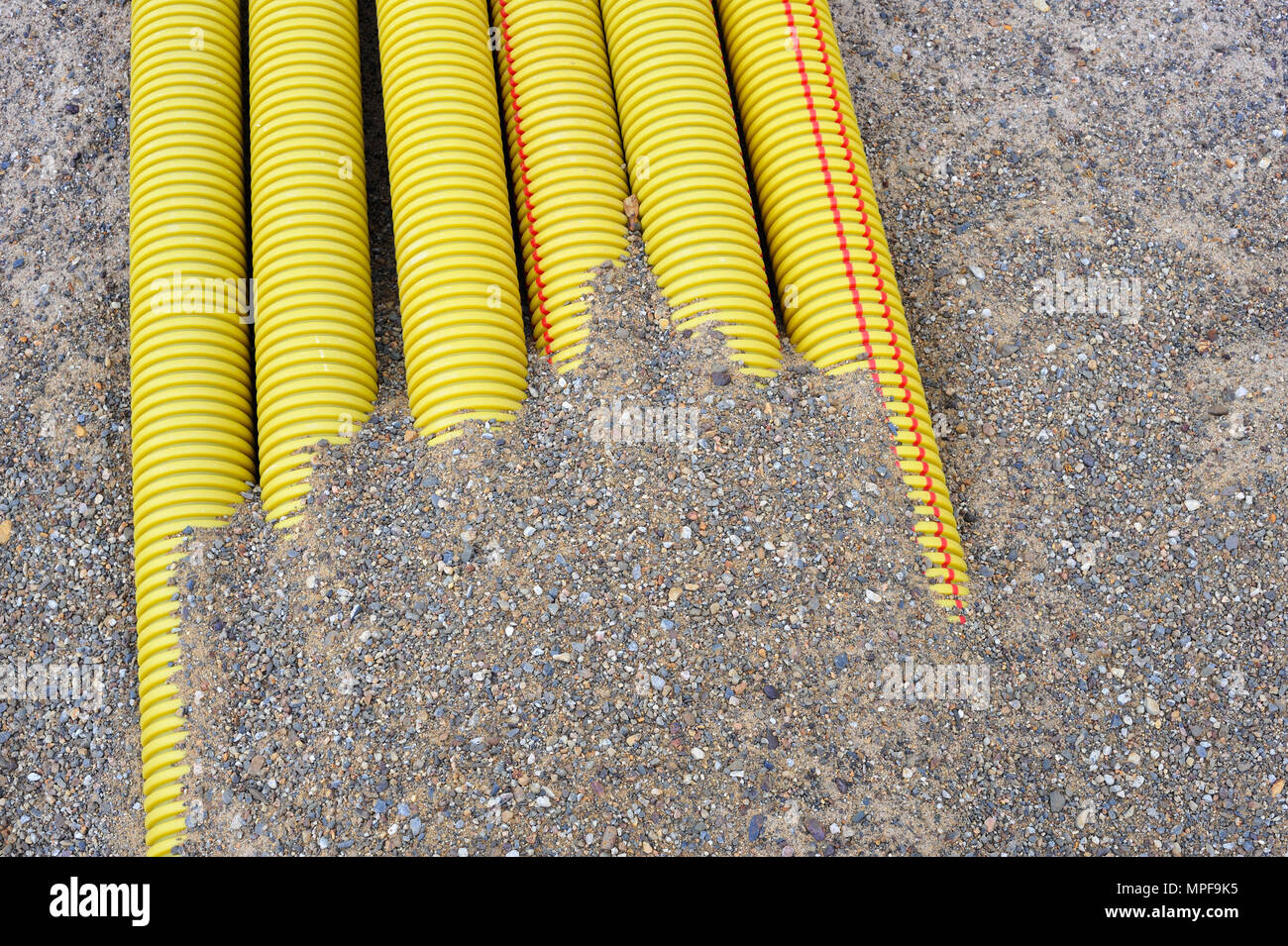 Yellow plastic tubes buried in the sand. Stock Photo