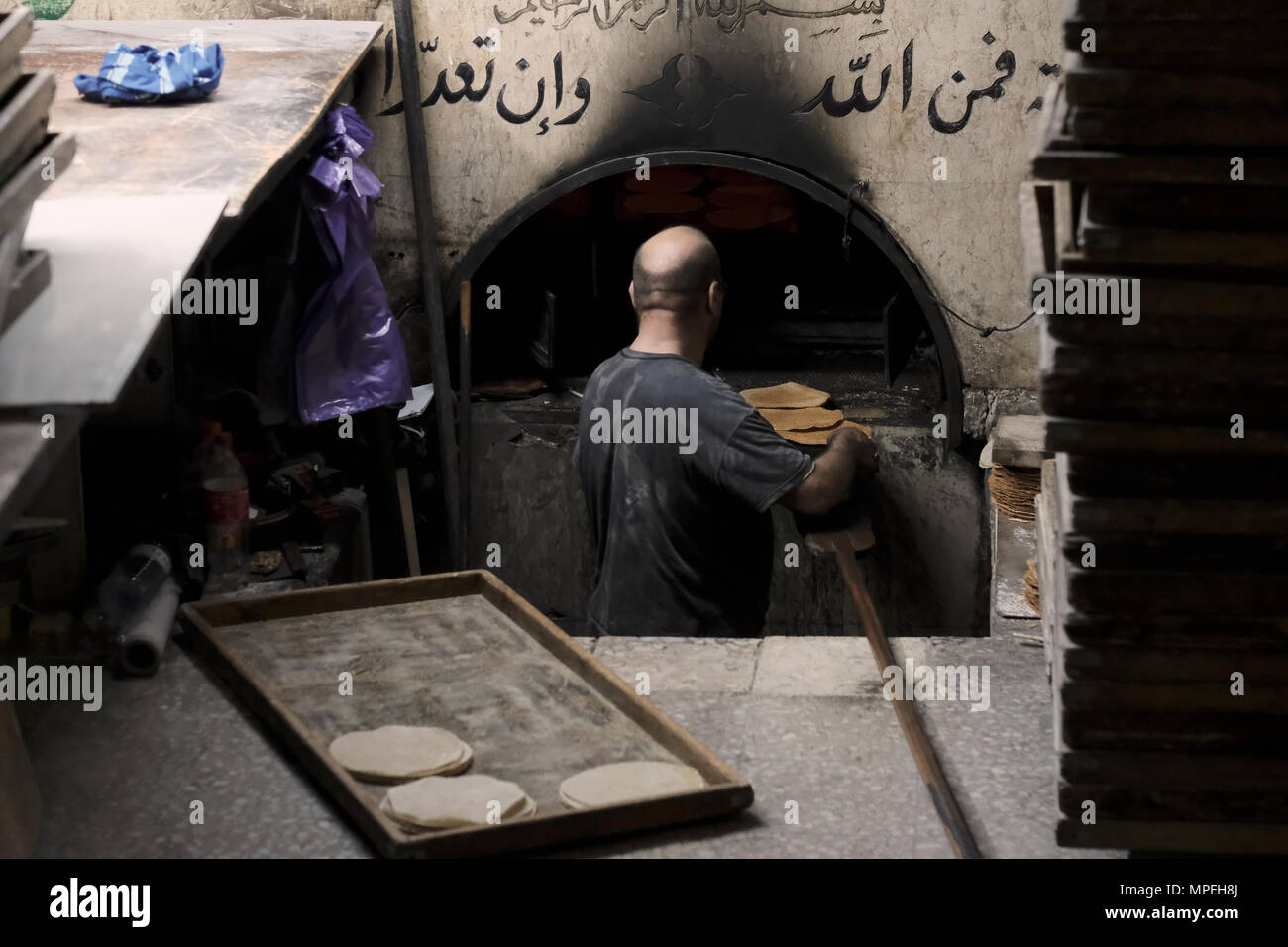 A Palestinian man baking traditional Pitta breads in a small bakery in