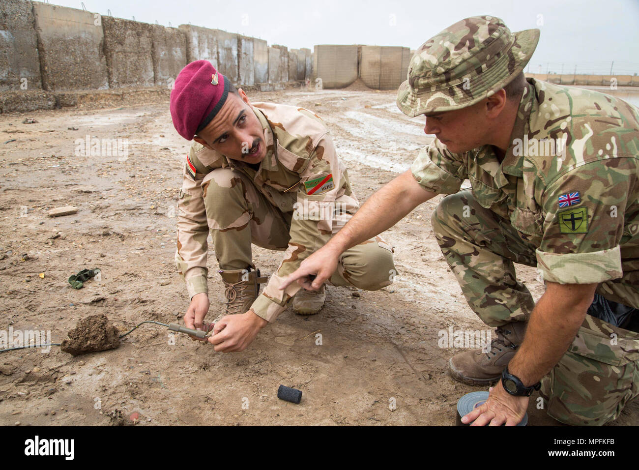 An Iraqi security forces soldier, prepares to trigger a water-forced disruption explosive to destroy a simulated improvised explosive device under the watchful eye of a British army explosive ordinance disposal soldier. British trainers assigned to 2nd Battalion, Duke of Lancaster Regiment and deployed in support of Combined Joint Task Force – Operation Inherent Resolve, conduct counter-IED training at Camp Taji, Iraq, April 9, 2017.   This training is part of the overall Combined Joint Task Force – Operation Inherent Resolve building partner capacity mission by training and improving the capa Stock Photo