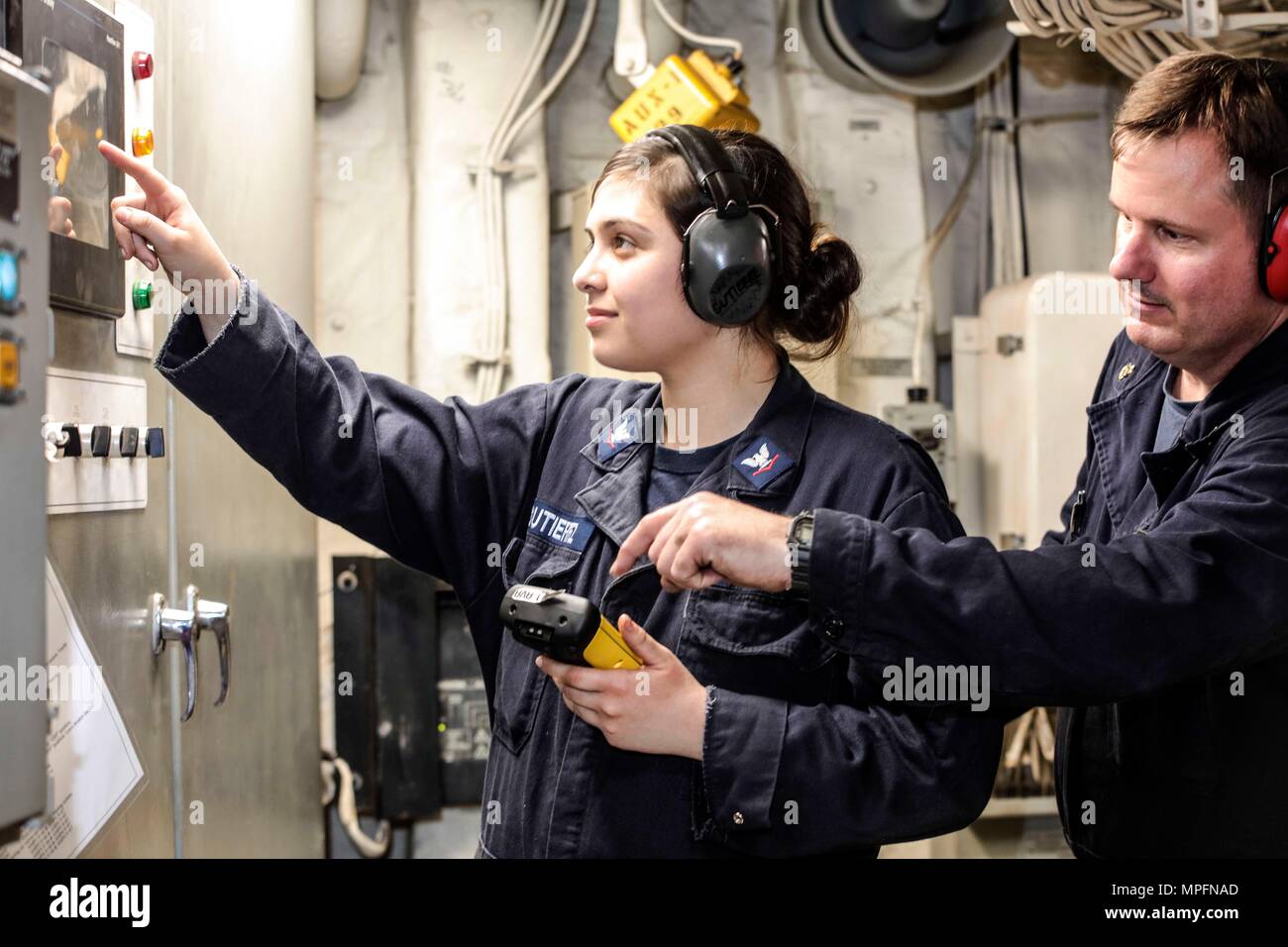 170304-N-FM530-078  ATLANTIC OCEAN (Mar. 4, 2017) Senior Chief Engineman Jason Lindsey oversees Engineman 3rd Class Nicole Gutierrez on taking readings of a diesel generator local control panel onboard amphibious transport dock ship, USS Mesa Verde (LPD 19) . Mesa Verde is deployed with the Bataan Amphibious Ready Group to support maritime security operations and theater security cooperation efforts in Europe and the Middle East. (U.S. Navy photo by Mass Communication Specialist 2nd Class Brent Pyfrom/Released) Stock Photo