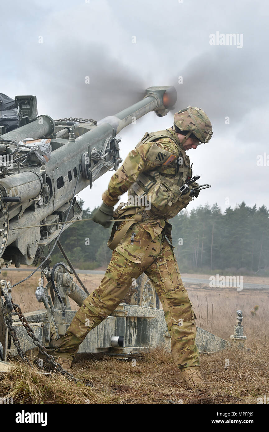 U.S. Army Spc. Vincent Ventarola, assigned to Cobra Battery, Field Artillery Squadron, 2nd Cavalry Regiment, pulls the lanyard on a M777 Howitzer during Exercise Dynamic Front II at the 7th Army Training Command's Grafenwoehr Training Area, Germany, March 9, 2017. Dynamic Front is an artillery operability exercise and focuses on developing solutions within the theater level fires system by executing multi-echelon fires and testing interoperability at the tactical level. It includes nearly 1,400 participants from nine NATO nations. (U.S. Army photo by Visual Information Specialist Gertrud Zach) Stock Photo