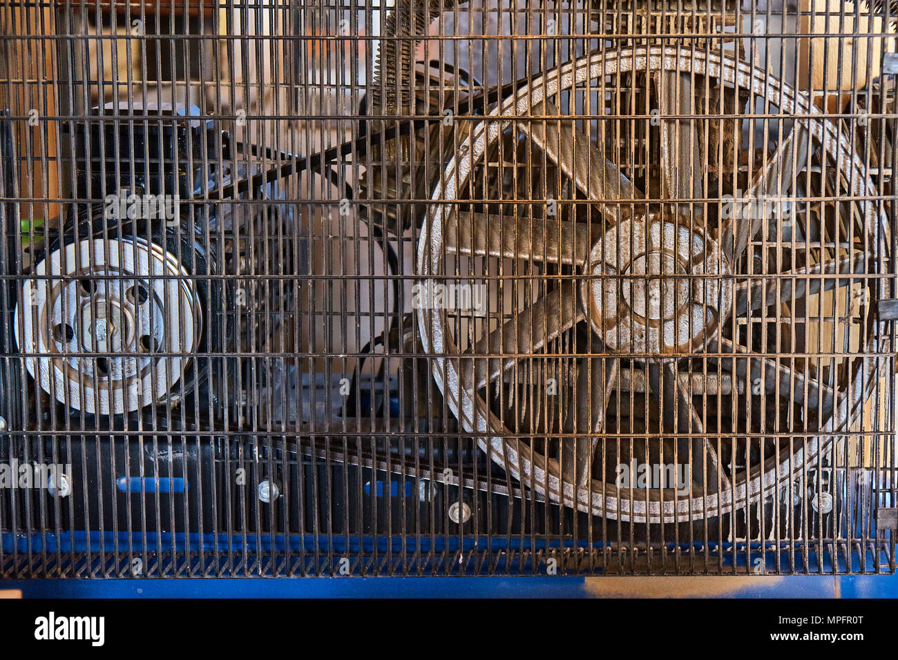 Electrical air compressor with a large fan in front panel behind a metal protective mesh Stock Photo