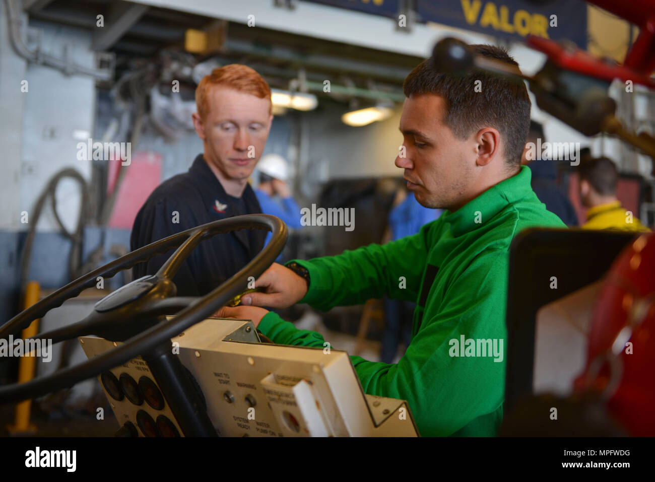 ATLANTIC OCEAN (March 9, 2017) – Aviation Support Equipment Technician 3rd Class Lane Nobile observes as Aviation Support Equipment Technician 2nd Class Matthew Fontenot repairs the control panel of an A/S32P-25A firefighting vehicle in the hangar bay aboard amphibious assault ship USS Iwo Jima (LHD 7). Iwo Jima is underway conducting a series of qualifications and certifications as part of the basic phase of training in preparation for future operations and deployments. (U.S. Navy photo by Mass Communication Specialist 2nd Class Andrew Murray/Released) Stock Photo
